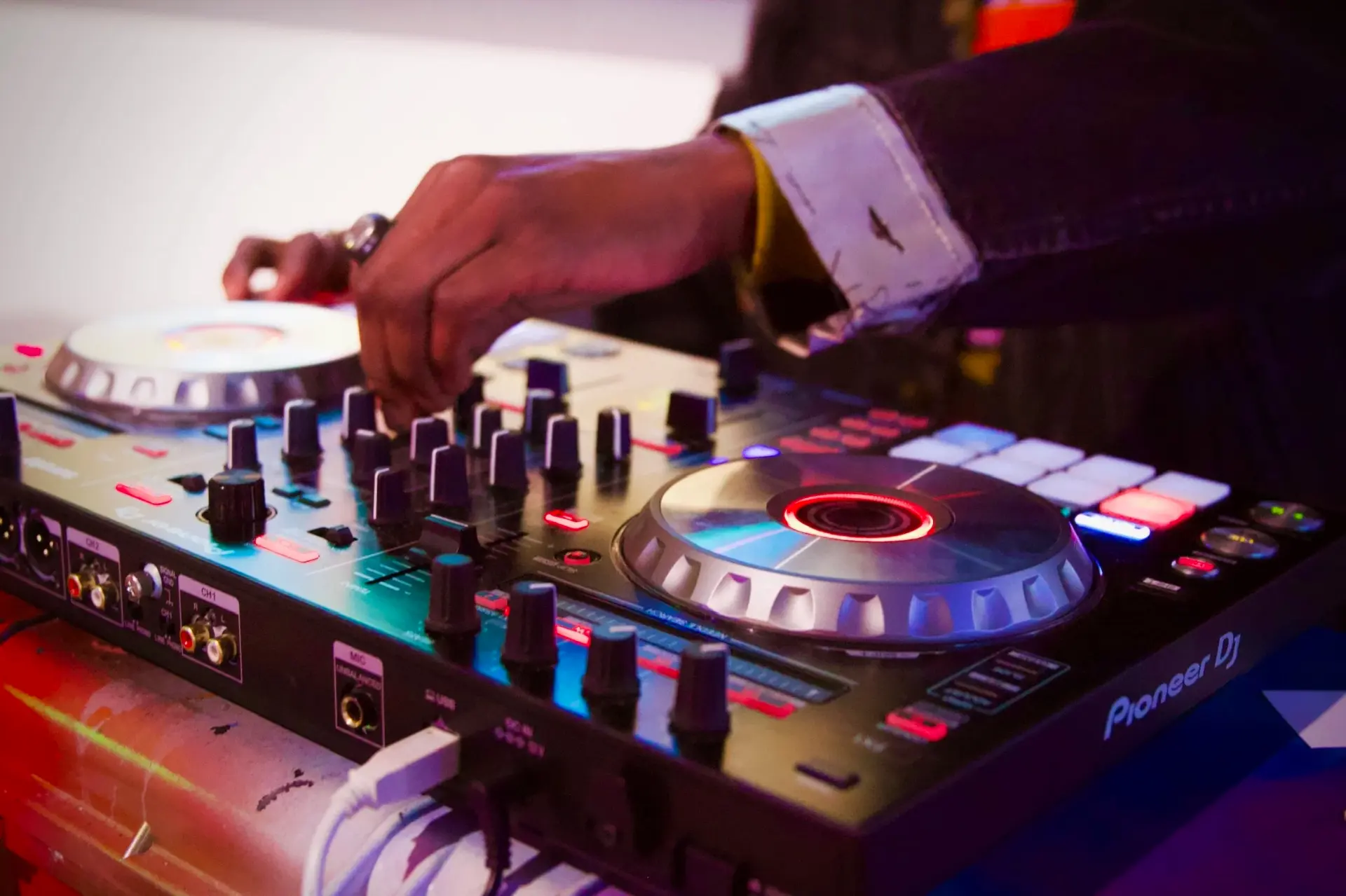 DJ mixing on a lit Pioneer controller during a live event
